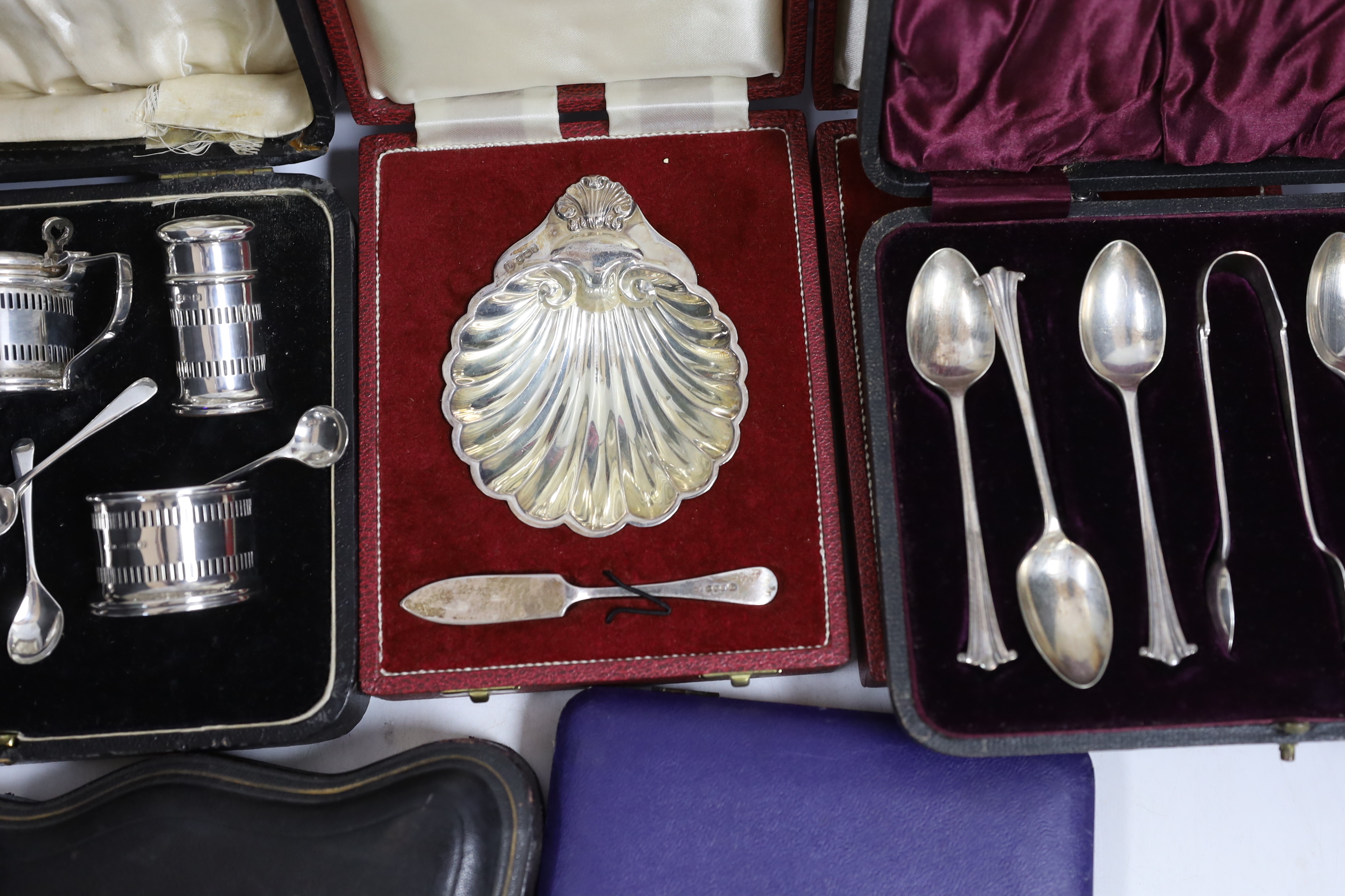 Two modern silver cased shell and butter knife sets, a cased silver five piece condiment set, a cased set of six silver teaspoons with tongs, one other cased silver butter shell and knife and a cased set of plated teaspo